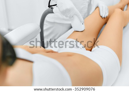 Body Care. Legs Laser Hair Removal. Beautician Removing Hair Of Young Woman\'s Leg. Laser Epilation Treatment In Cosmetic Beauty Clinic. Hairless Smooth And Soft Skin. Health And Beauty Concept.