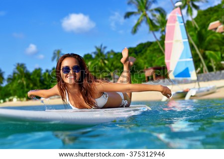 Summer Adventure. Water Sports. Happy Carefree Sexy Woman In Bikini Surfing, Lying On Paddle, Surf Board In Sea At Exotic Resort. Holidays Travel Vacation. Healthy Active Lifestyle. Leisure Activity.