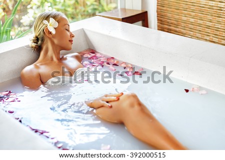 Spa Relaxation. Woman Body Care. Beautiful Sexy Caucasian Blonde Girl In Bikini Lying In Flower Bath In Resort Day Spa Salon. Beauty Treatment, Skin Care Therapy. Wellness. Healthy Lifestyle Concept