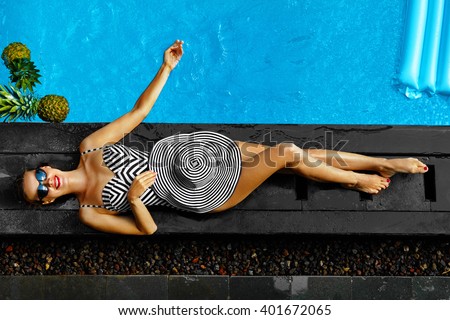 Woman Summer Fashion. Happy Sexy Smiling Girl With Fit Body, Long Legs, Healthy Skin In Bikini, Sun Hat, Sunglasses Sunbathing By Swimming Pool On Travel Holidays Vacation. Beauty, Wellness, Lifestyle