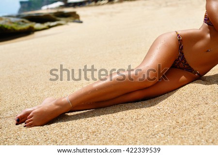 Woman Legs On Beach. Beautiful Sexy Girl With Slim Fit Body, Healthy Smooth Silky Sun Tanned Skin And Long Depilated Legs Relaxing On Sand. Female In Bikini Sunbathing In Summer. Human Body Part