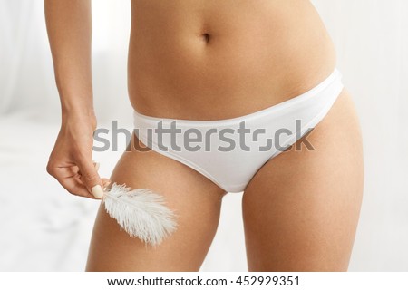 Women Health And Intimate Hygiene. Closeup Of Beautiful Woman's Body With Smooth Soft Skin In White Bikini Panties. Female Hand Touching Her Thigh Hip With White Feather. Body Care, Epilation Concepts