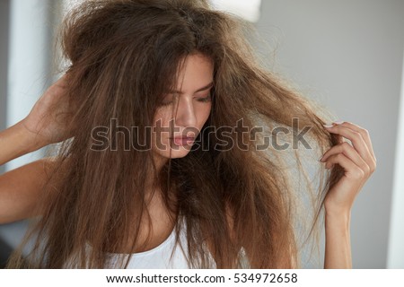Damaged Hair. Beautiful Sad Young Woman With Long Disheveled Hair. Closeup Portrait Of Female Model Holding Messy Unbrushed Dry Hair In Hands. Hair Damage, Health And Beauty Concept. High Resolution