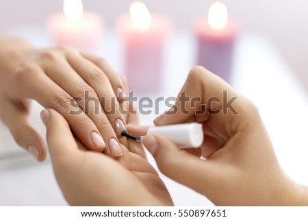 Nail Care And Manicure. Closeup Of Beautiful Female Hands Applying Transparent Nail Polish On Healthy Natural Woman\'s Nails In Beauty Salon. Manicurist Hand Painting Client\'s Nails. High Resolution
