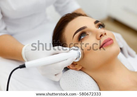 Cosmetology. Beautiful Woman Receiving Facial Skin Ultrasound Cavitation. Closeup Of Female Face Receiving Anti-Aging Cosmetics Using Ultrasound Cavitation Machine. Body Care. High Resolution