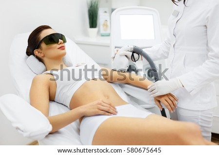 Woman Beauty. Beautician Doing Epilation On Beautiful Girl\'s Body In Medical Center. Female Receiving Laser Light Hair Removal Treatment For Hairless Smooth Skin At Cosmetology Salon. High Resolution