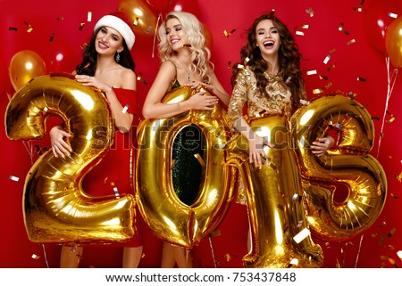 Beautiful Women Celebrating New Year. Happy Gorgeous Girls In Stylish Sexy Party Dresses Holding Gold 2018 Balloons, Having Fun At New Year\'s Eve Party. Holiday Celebration. High Quality Image