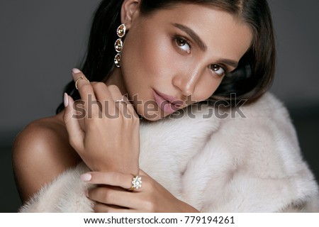 Jewelry Fashion. Woman In Luxury Jewels. Glamour Female Model With Beauty Face Makeup Wearing Expensive Gold Jewelry And Stylish Beige Mink Fur Coat. High Quality Image.