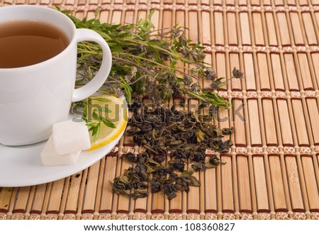 green tea with herbs and lemon on bamboo mat background