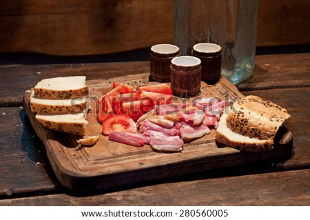 Bacon, tomato, bread and vodka on the table