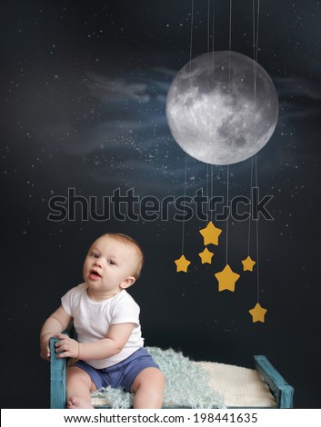 Baby sitting in bed, looking at the moon and stars mobile, starry night. Nap time, sleeping concept