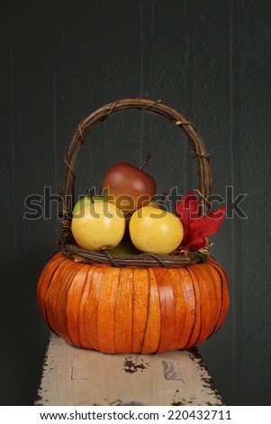Apples in basket on rustic wood bench on textured background, fall or thanksgiving theme