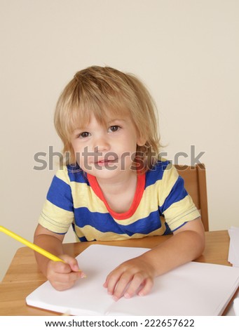 Toddler boy engaged in art and craft with pencils and paper, learning and education concept
