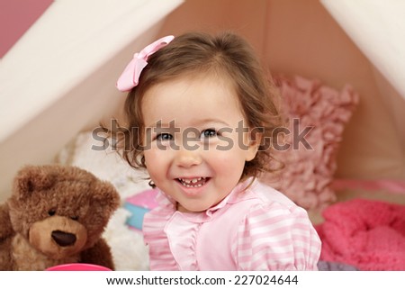 Happy toddler girl engaged in pretend play at home with a teepee tent
