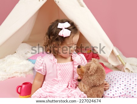 Happy toddler girl engaged in pretend play at home with a stuffed bear toy