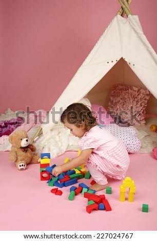 Happy toddler girl engaged in pretend play at home with blocks