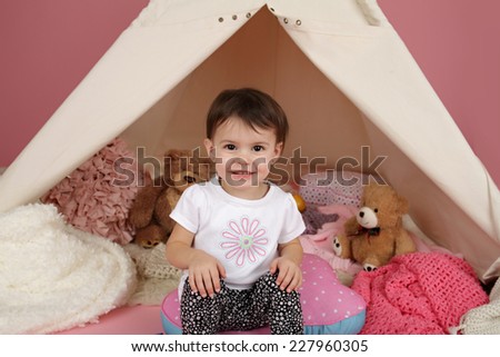 Toddler child, kid, engaged in pretend play with stuffed toys, and teepee tent