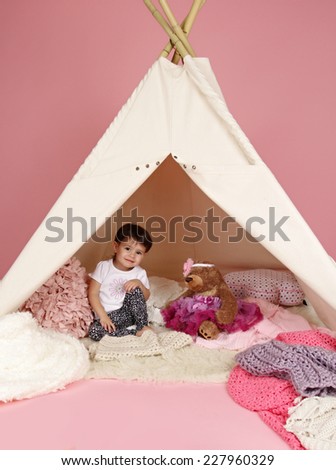 Toddler child, kid, engaged in pretend play with stuffed toys, and teepee tent