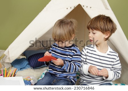 Kids engaged in arts and crafts activity, playing in a teepee tent at home