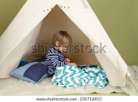 Child playing at home in a tent, drawing and art activity, showing a blank page