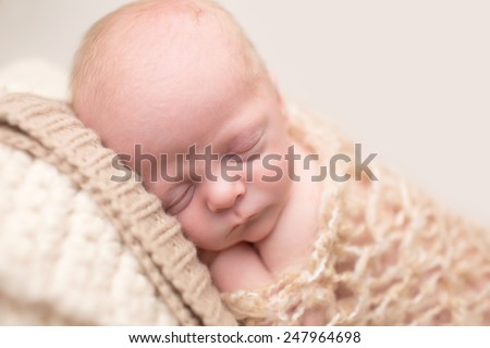 Newborn Baby Asleep, sleeping and taking a nap on a textured blanket posed and curled up