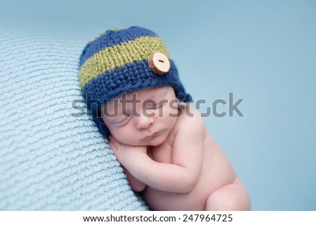 Sleeping newborn baby boy, infant, on a blue knit blanket, posed asleep during nap time