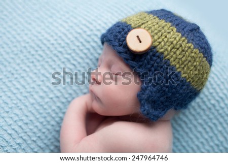 Sleeping newborn baby boy, infant, on a blue knit blanket, posed asleep during nap time