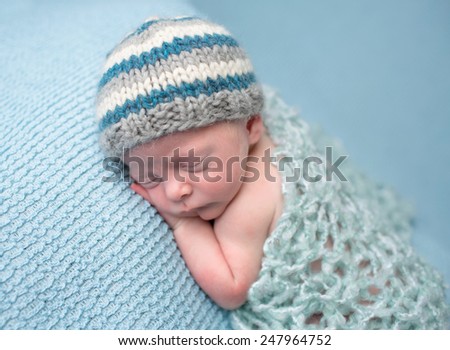Newborn infant baby asleep posed on a blanket, in a knit wrap