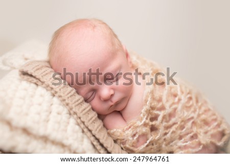 Newborn Baby Asleep, sleeping and taking a nap on a textured blanket posed and curled up