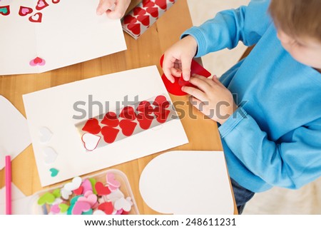 Childs, kids, engaged in a Valentine\'s Day arts and crafts activity