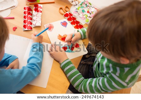 Kids, children, doing Valentine\'s day arts and crafts with hearts, pencils, paper