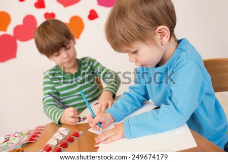 Kids, children, doing Valentine\'s day arts and crafts with hearts, pencils, paper, love concept