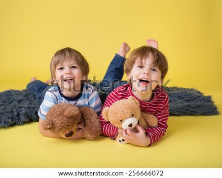 Two happy kids hugging stuffed toy animals, laughing. Siblings, brothers or friends.