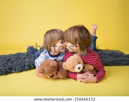 Two happy kids hugging stuffed toy animals, laughing. Siblings, brothers or friends.