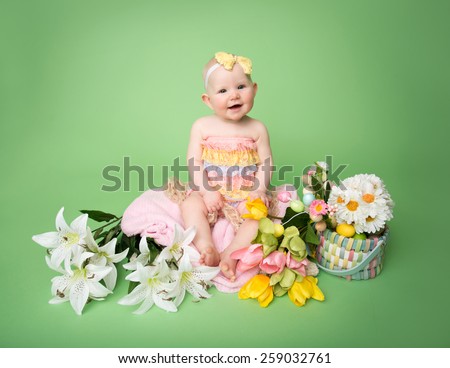 Baby girl in Easter outfit with Easter Eggs, and tulip flowers, sitting on blanket