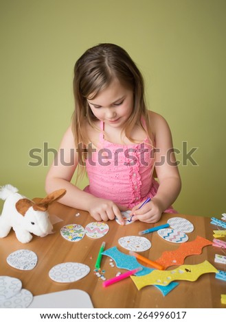 Child doing Easter activities and crafts with bunny stickers, Easter Egg shapes, pencils and markers.