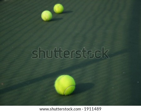 View of yellow tennis balls on green tennis court