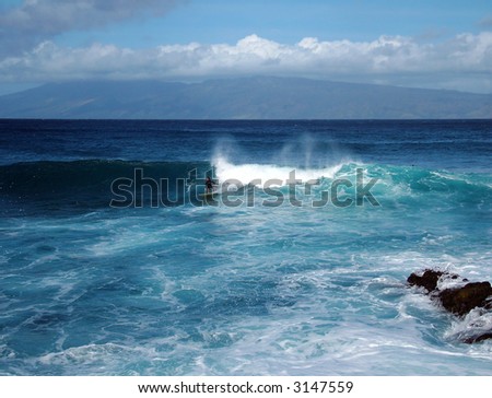View of a surf rider on blue ocean, tropical waves, blue sky and Hawaii island in the background