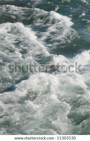 Rapid river flow, waves, gushing water. Suitable for a variety of environmental projects, as water background or as texture overlay.