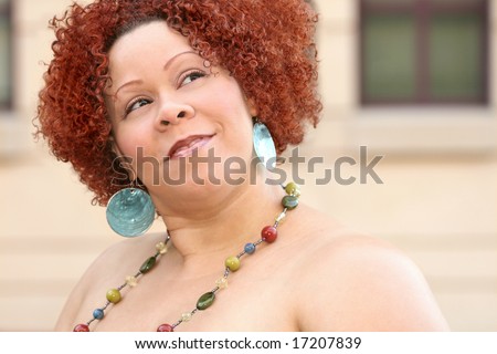 Portrait of a plus size female with short curly red hair and bright jewelry