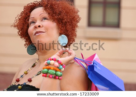 Plus size model, smiling about a purchase and looking into a shopping bag.