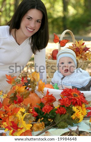 Portrait of a young mother and her blue-eyed baby boy with fall leaves, pumpkins and bright flowers, outdoors in a park, suitable for a variety of seasonal and family themes