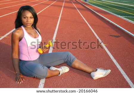 Young attractive African American female working out outdoors at a stadium, track