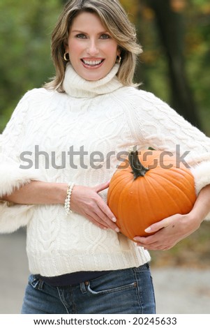 Gorgeous caucasian woman with a pumpkin enjoying a great day in a park, seasonal theme