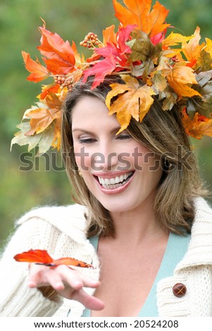 Gorgeous caucasian woman with fall leaves and a butterfly enjoying a great day in a park, seasonal theme
