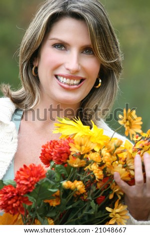 Gorgeous caucasian woman with fall leaves and flowers enjoying a great day in a park, seasonal theme