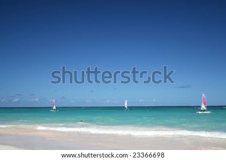 Sailboats in ocean - Beautiful Caribbean tropical beach with white sand and green waves. FOCUS on sailboats