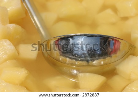 ladle dipping into pineapples chunks and juice