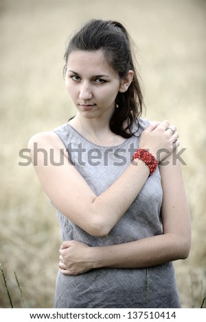 Young woman in a grey linen dress posing in the field