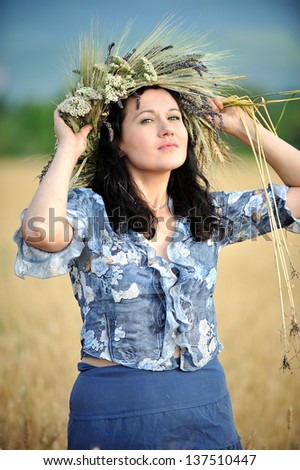 Woman with a flower crown in the wheat field looking at the camera